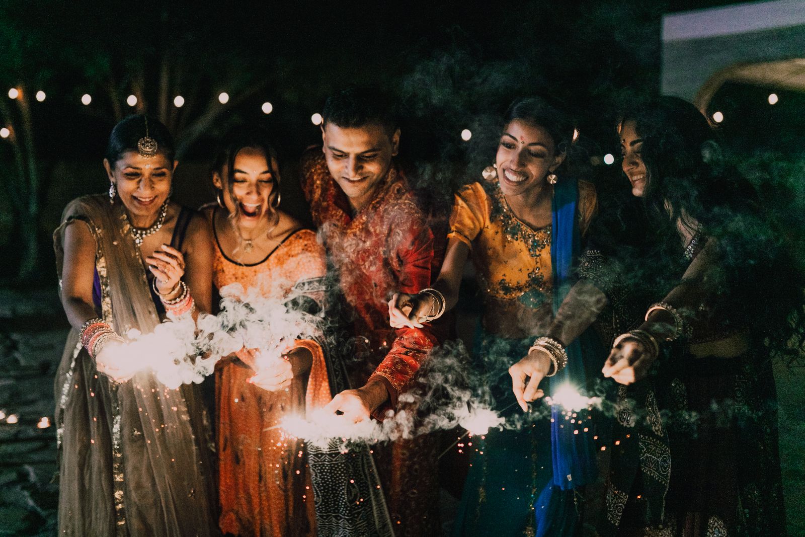 Friends in traditional wear holding sparklers at night